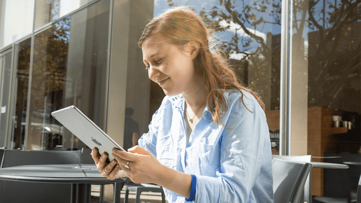 Person sitting outdoors looking at  Apple iPad Person sitting outdoors looking at  Apple iPad