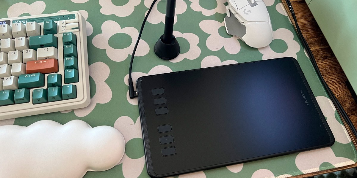 HUION Inspiroy H640P on desk with green and white background HUION Inspiroy H640P on desk with green and white background