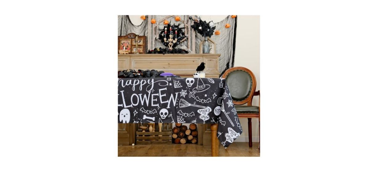 black plastic tablecloth with the words &quot;Happy Halloween&quot; on it and various spooky designs also in white