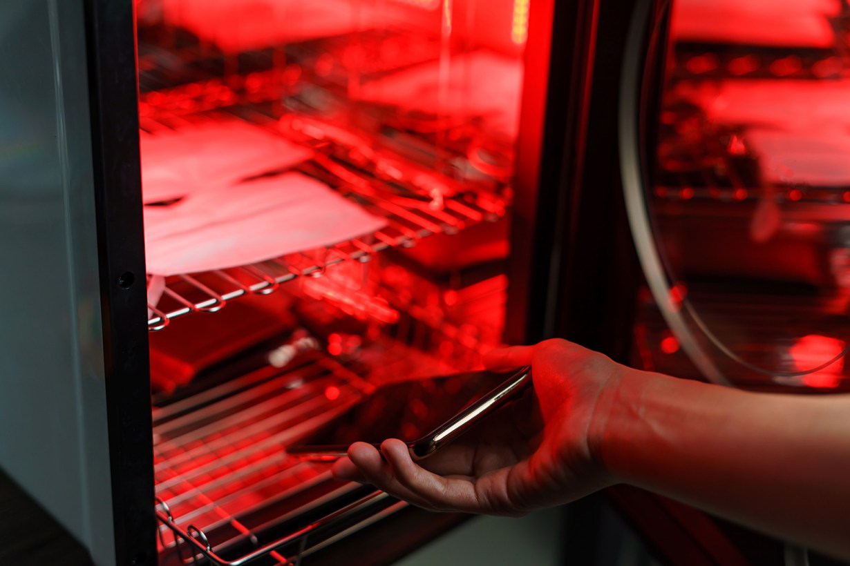 a hand putting a smartphone inside a uv sanitizer