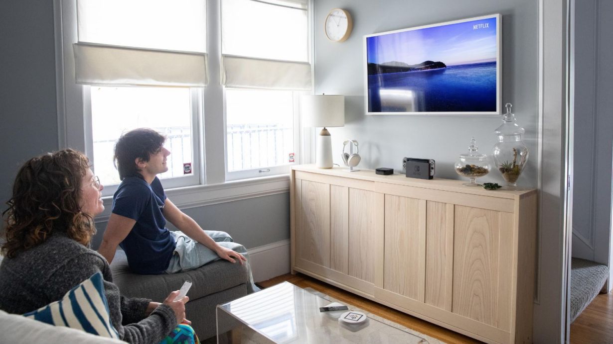 Man and woman sitting on a couch watching a Samsung Frame TV